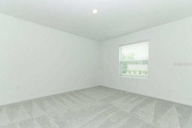 empty room featuring baseboards, recessed lighting, and light colored carpet