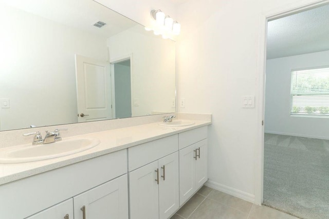 bathroom featuring double vanity, visible vents, baseboards, and a sink