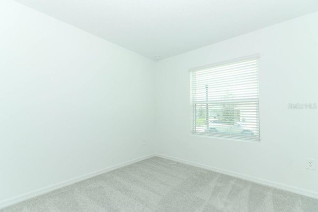 unfurnished room with light carpet and baseboards