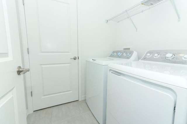 washroom with light tile patterned floors, washing machine and clothes dryer, and laundry area