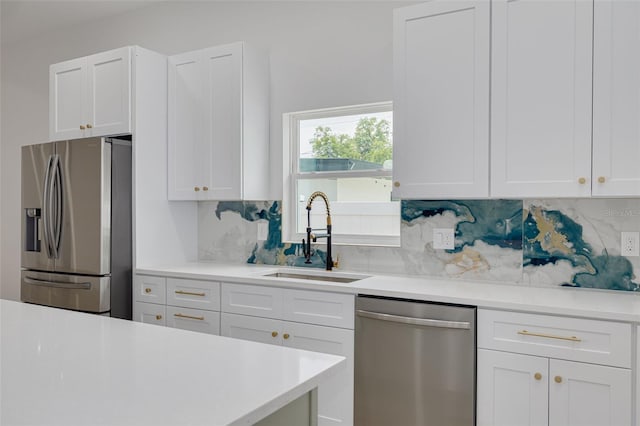 kitchen with a sink, tasteful backsplash, white cabinetry, light countertops, and appliances with stainless steel finishes
