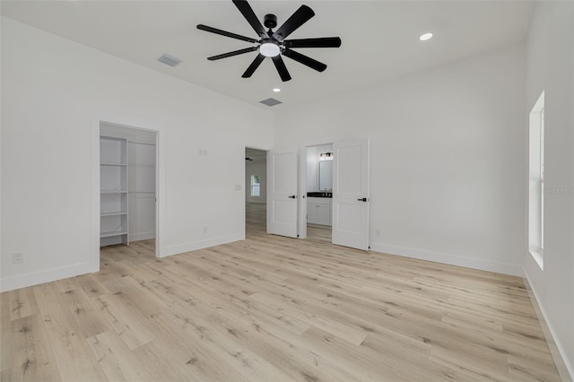 unfurnished bedroom with recessed lighting, a walk in closet, and light wood-style flooring