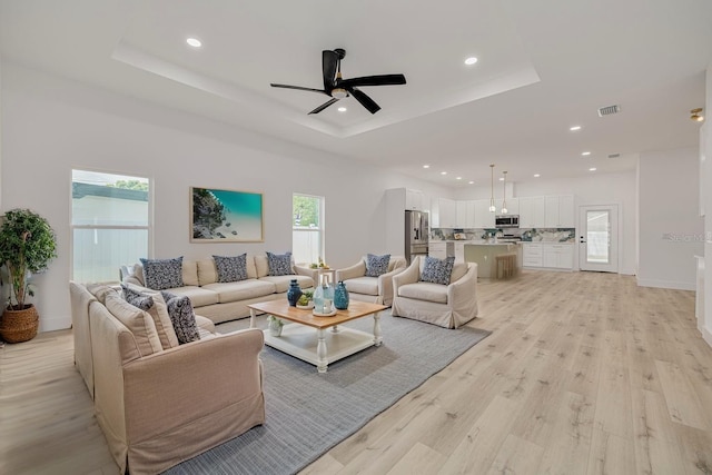 living area with visible vents, a raised ceiling, and recessed lighting