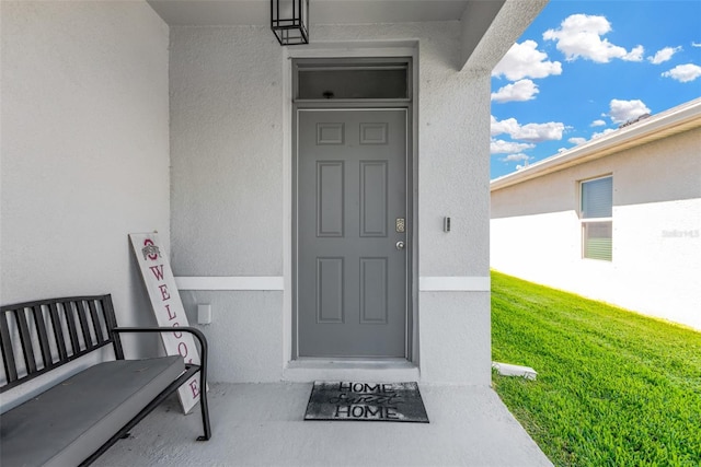 entrance to property featuring a yard and stucco siding