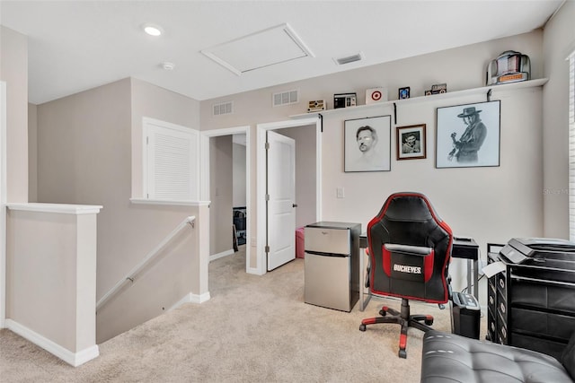 carpeted home office with visible vents, baseboards, and attic access