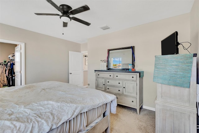 bedroom with ceiling fan, a spacious closet, visible vents, light carpet, and baseboards
