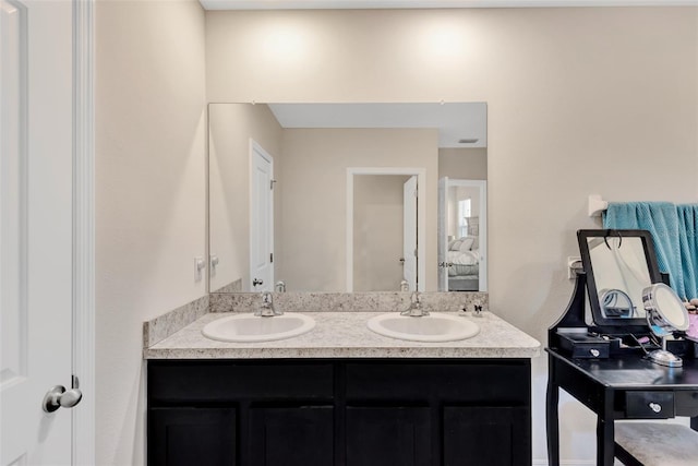 bathroom with double vanity, a sink, and connected bathroom