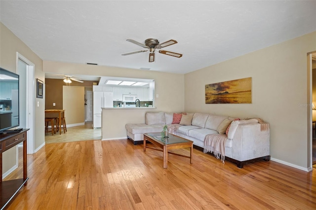 8763 Matthew St, Seminole, FL 33772 - living area featuring ceiling fan, light wood-style floors, and baseboards