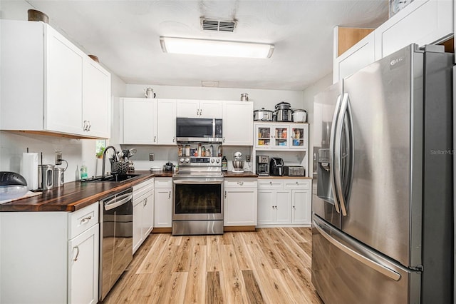 186 Grand Ave, Brooksville, FL 34604 - kitchen with appliances with stainless steel finishes, a sink, light wood finished floors, and white cabinetry