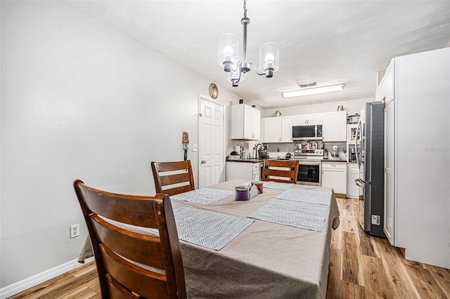 186 Grand Ave, Brooksville, FL 34604 - dining room featuring a chandelier, light wood-style flooring, and baseboards