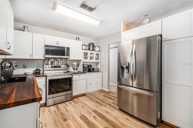 186 Grand Ave, Brooksville, FL 34604 - kitchen with stainless steel appliances, a sink, wooden counters, light wood-style flooring, and white cabinetry