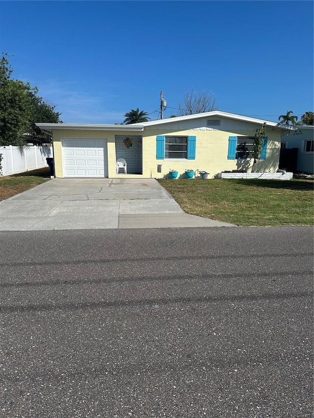 ranch-style house featuring an attached garage, concrete driveway, a front yard, and fence