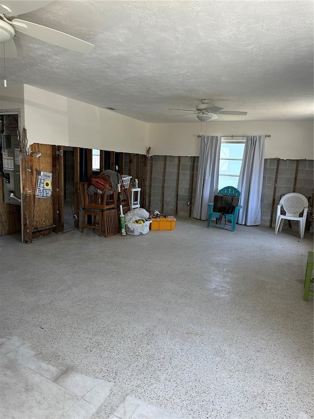interior space featuring a textured ceiling, a ceiling fan, heating unit, and speckled floor