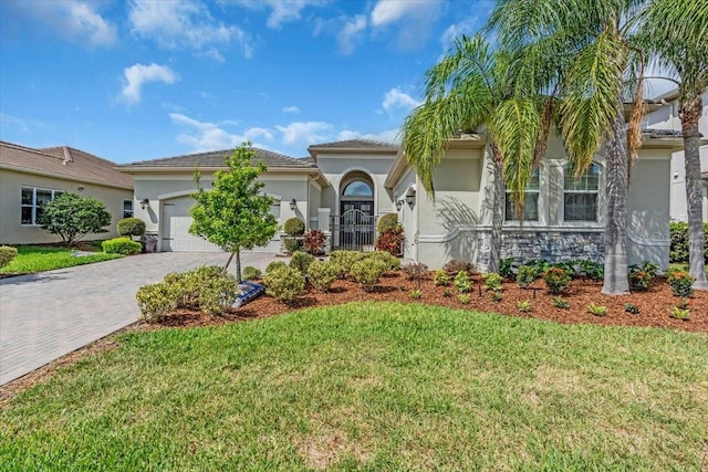 view of front of house with stucco siding, decorative driveway, stone siding, a front lawn, and a garage