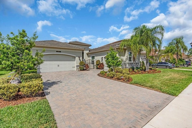 mediterranean / spanish home featuring a garage, stucco siding, a front yard, and decorative driveway