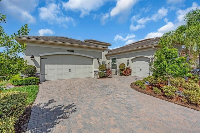 mediterranean / spanish-style house with driveway, a gate, a garage, and stucco siding