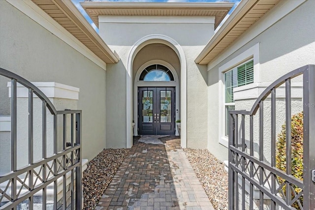 view of exterior entry featuring french doors and stucco siding