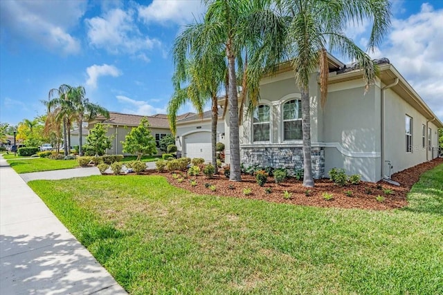 view of front of property featuring an attached garage, stucco siding, and a front lawn