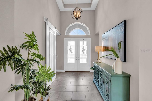 foyer entrance with a notable chandelier, baseboards, tile patterned floors, french doors, and a high ceiling