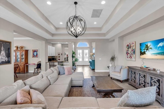 living room with baseboards, a chandelier, recessed lighting, visible vents, and a tray ceiling