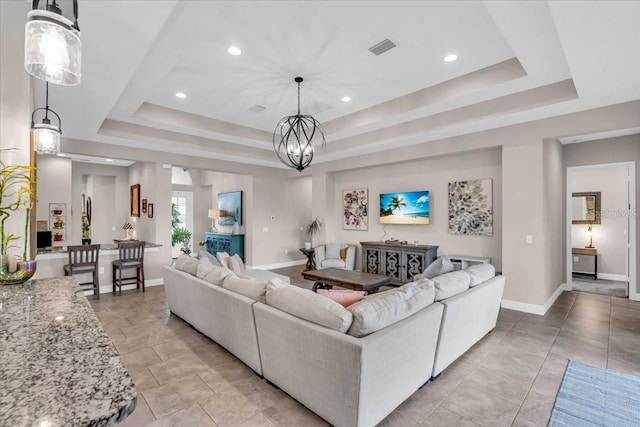 living room featuring a tray ceiling, baseboards, visible vents, and recessed lighting