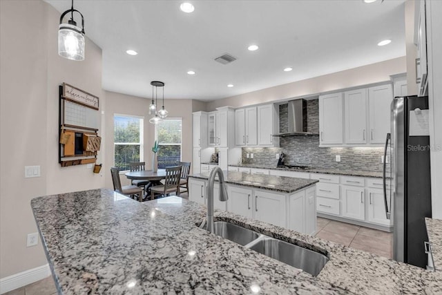 kitchen featuring visible vents, light tile patterned floors, a sink, wall chimney range hood, and appliances with stainless steel finishes