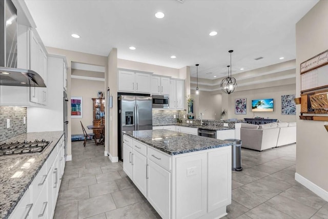 kitchen featuring a peninsula, wall chimney range hood, backsplash, and stainless steel appliances