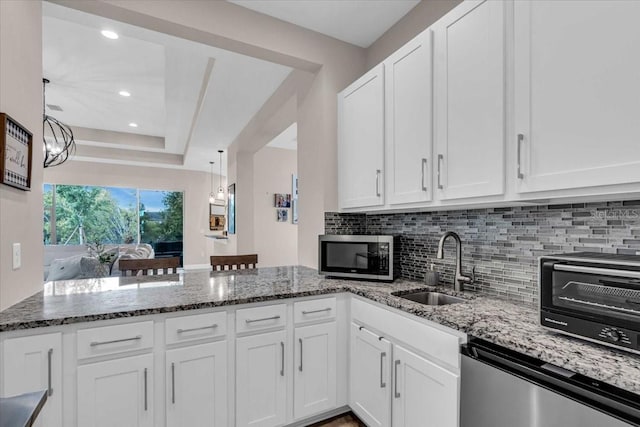 kitchen with a peninsula, white cabinetry, and stainless steel appliances