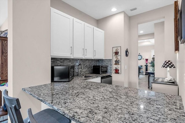 kitchen featuring a sink, decorative backsplash, white cabinetry, and light stone counters