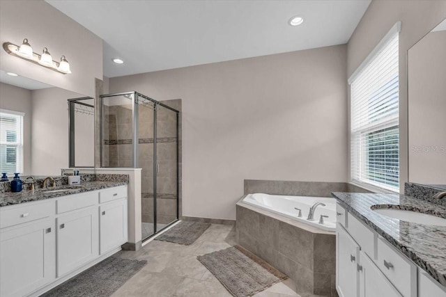 bathroom featuring a wealth of natural light, a garden tub, a sink, and a stall shower