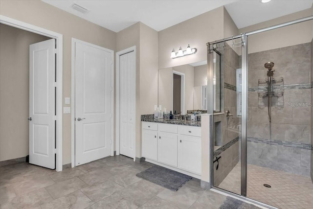 bathroom featuring a shower stall, vanity, visible vents, and baseboards