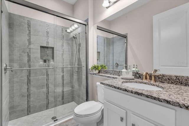 bathroom featuring toilet, a stall shower, and vanity
