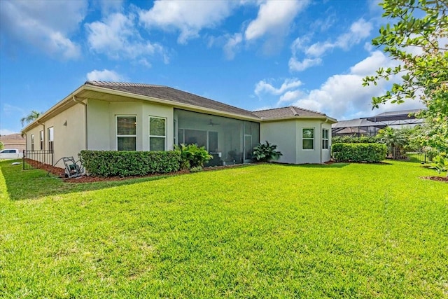 rear view of house featuring stucco siding, fence, and a lawn