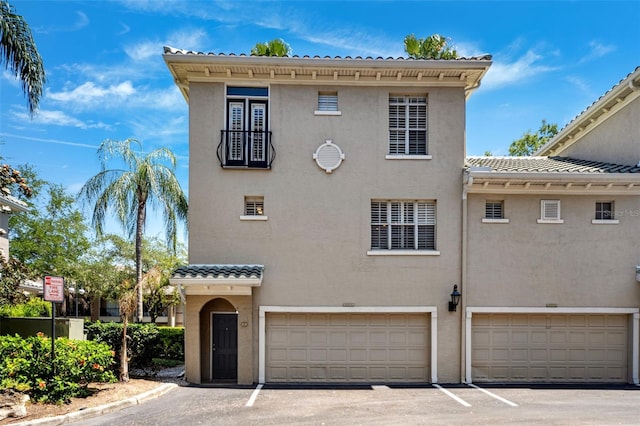 view of front facade featuring a garage, driveway, stucco siding, and a tile roof