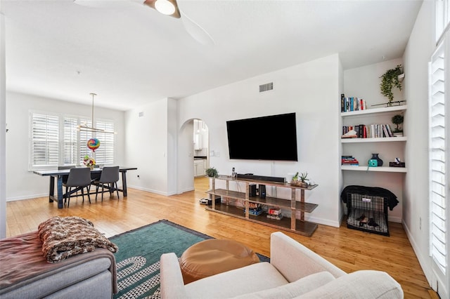 living room with arched walkways, ceiling fan, visible vents, and wood finished floors