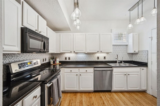 kitchen featuring dark countertops, a sink, white cabinetry, and stainless steel appliances