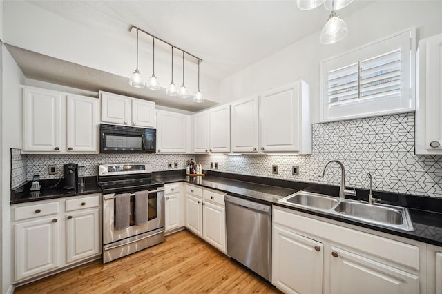 kitchen with white cabinets, dark countertops, a sink, stainless steel appliances, and decorative backsplash