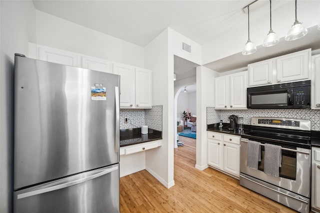 kitchen featuring visible vents, white cabinets, arched walkways, dark countertops, and stainless steel appliances