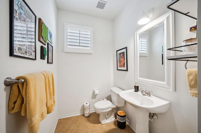 half bath featuring baseboards, tile patterned flooring, toilet, visible vents, and a sink