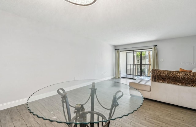 unfurnished living room featuring baseboards, wood finished floors, and a textured ceiling
