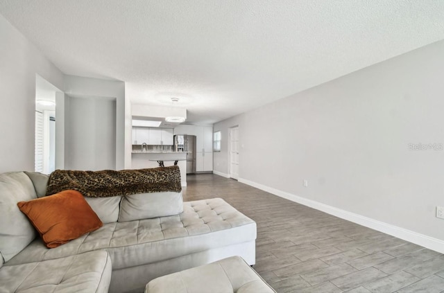 living room featuring baseboards, a textured ceiling, and wood finished floors
