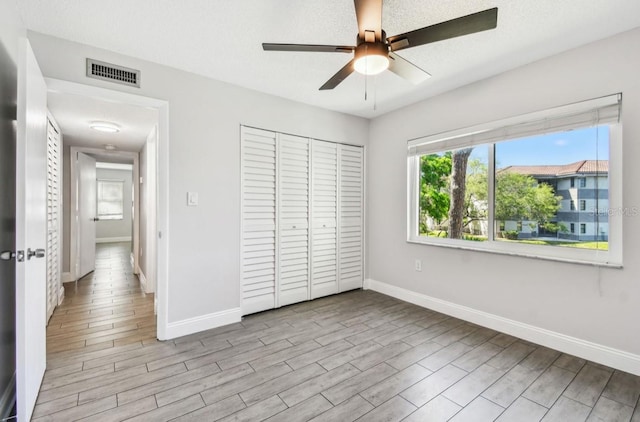 unfurnished bedroom with a closet, visible vents, baseboards, and wood finished floors