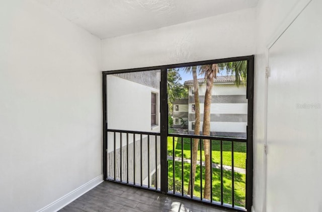 doorway with baseboards, plenty of natural light, and wood finished floors