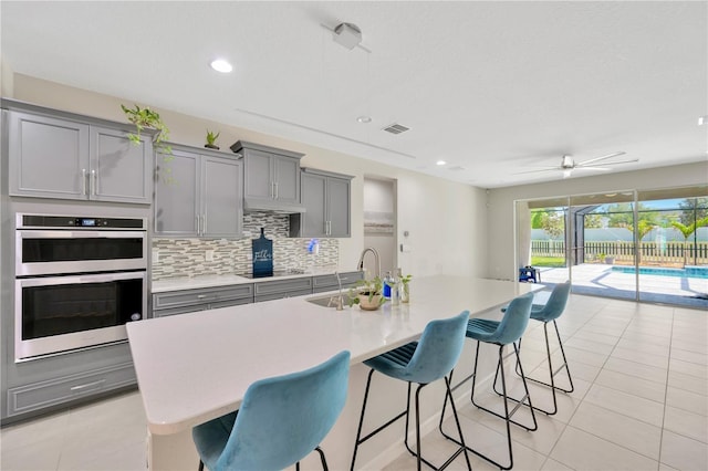 2511 Early Dawn Ct, Valrico, FL 33594 - kitchen with stainless steel double oven, visible vents, a sink, light tile patterned flooring, and gray cabinetry