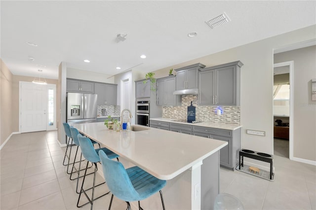 2511 Early Dawn Ct, Valrico, FL 33594 - kitchen featuring tasteful backsplash, visible vents, gray cabinetry, under cabinet range hood, and appliances with stainless steel finishes