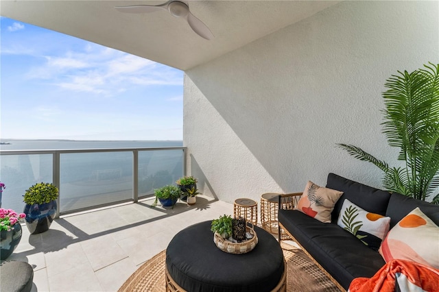 balcony with an outdoor living space, a ceiling fan, and a water view