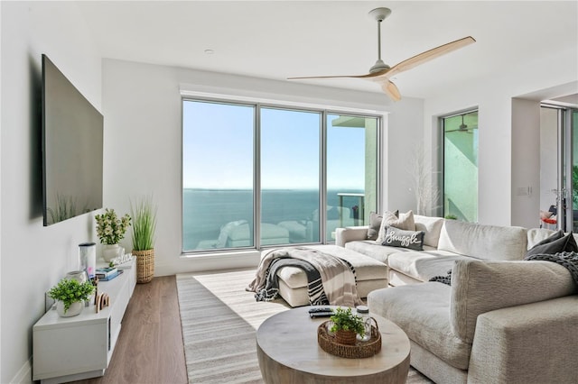 living area featuring wood finished floors, ceiling fan, and a water view