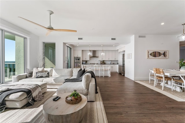 living area with a ceiling fan, dark wood finished floors, visible vents, and recessed lighting
