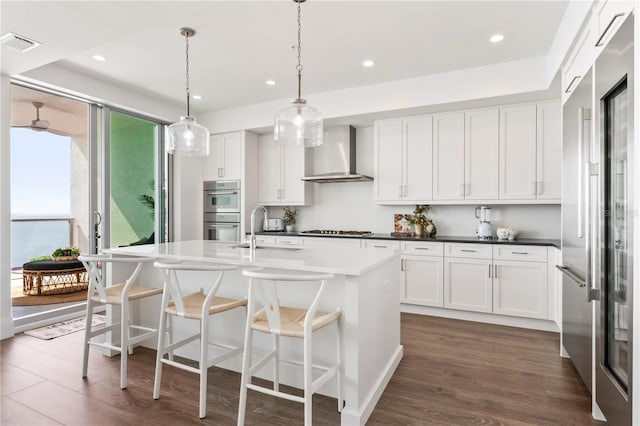 kitchen featuring recessed lighting, visible vents, wall chimney exhaust hood, stainless steel appliances, and a sink