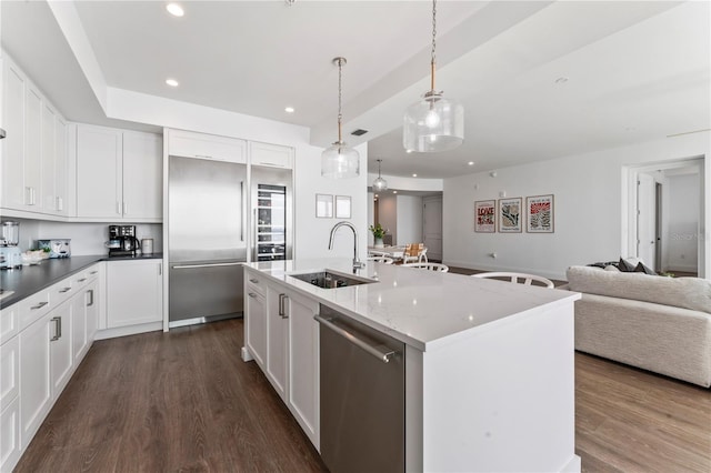 kitchen with a sink, open floor plan, appliances with stainless steel finishes, and dark wood-style floors